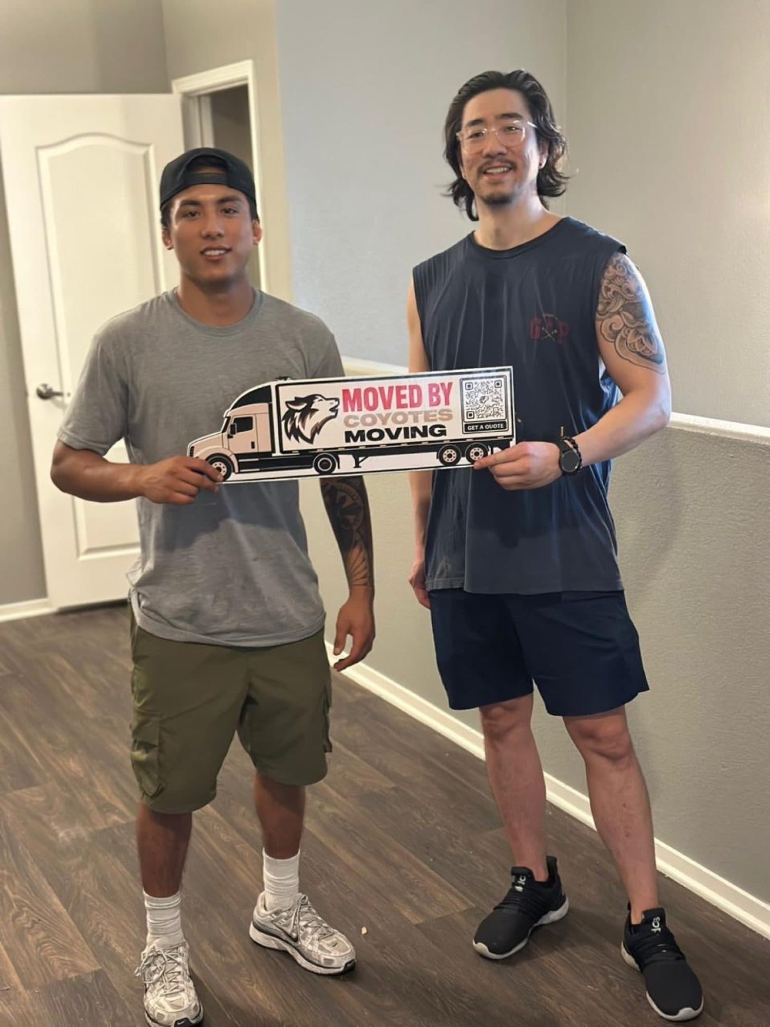 Coyotes Moving customers holding the "Moved By Coyotes Moving" sign