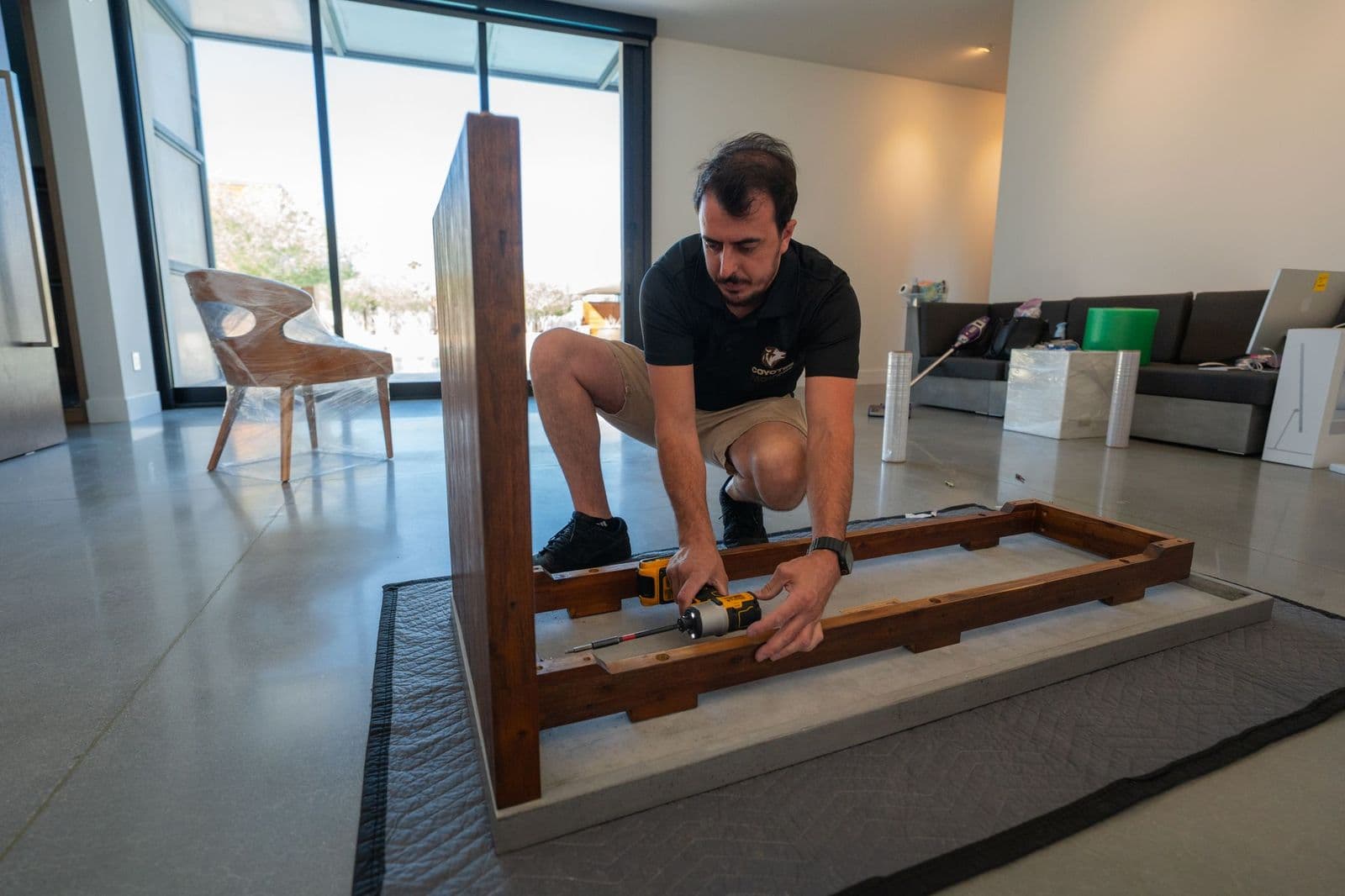 Coyotes Movers crew member assembling a wooden furniture frame, hardware bagged and labeled by piece